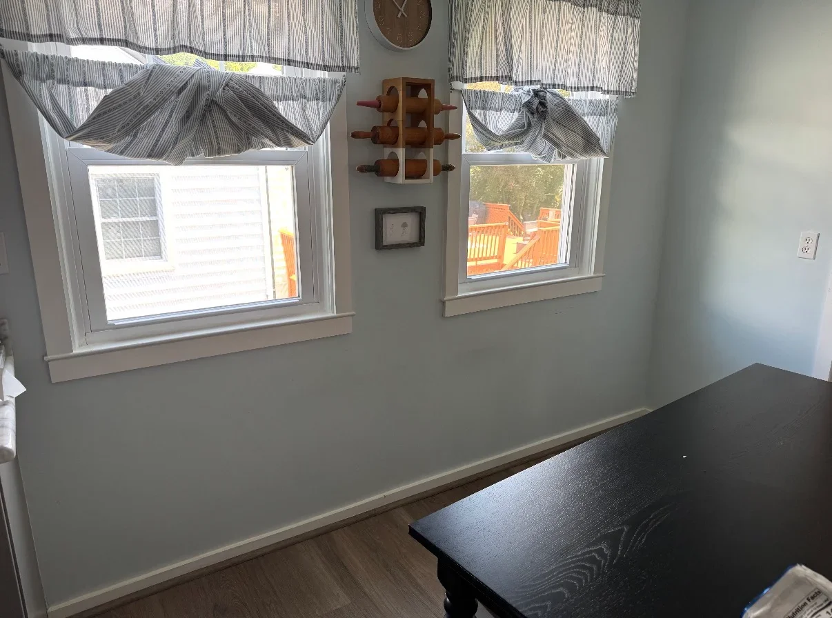 Two white-trimmed double-hung windows with roman shade valances and finished interior trim
