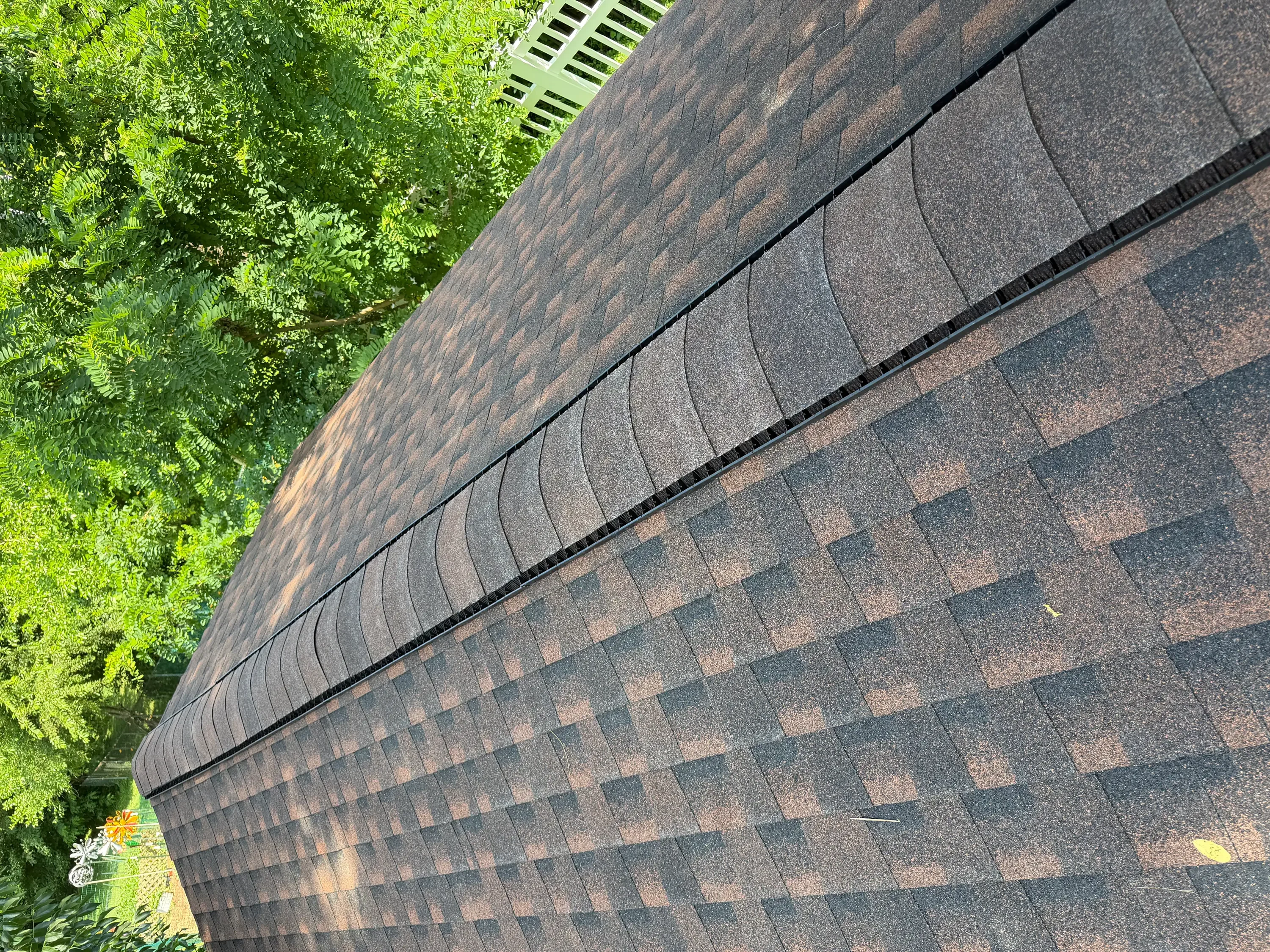Architectural shingles in gray and brown tones installed with offset pattern and black drip edge